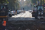 Straßenbauarbeiten mit einem Bauarbeiter und parkenden Autos an einer Straße