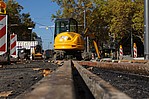 Gelber Bagger auf einer Schienenstraße mit Absperrpfosten