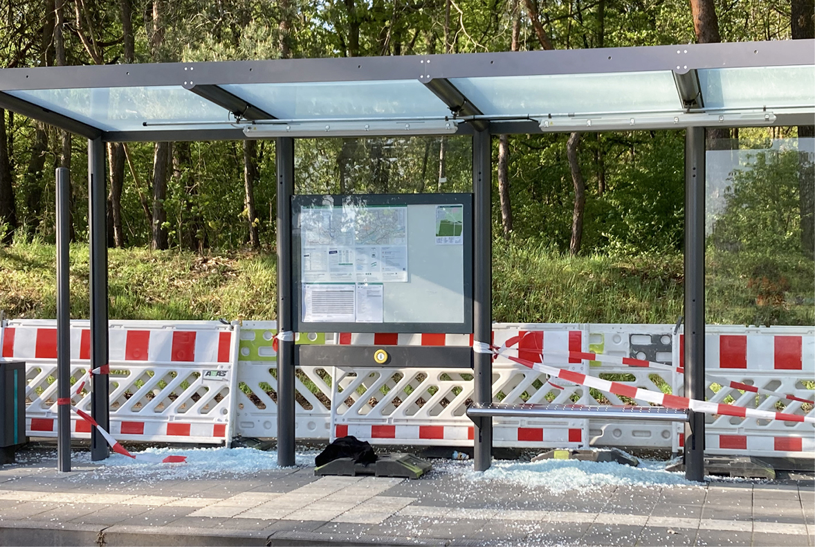 Zerbrochene Glasscheiben an einer Haltestelle mit rot-weissem Absperrband