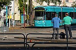Zwei wartende Passanten und die VGF-Bahn an einer Haltestelle