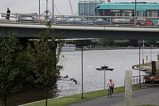 VGF-Bahn beim grauen Wetter am Main in Frankfurt, die über eine Brücke fährt