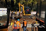 Bauarbeiter bei der Arbeit an einer Straße mit gelben Bagger