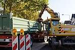 Grüner Container und gelber Bagger im Arbeitsmodus
