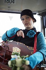 Frau mit schwarzer Mütze und blauer Rosenbrosche und Tasche mit Gewinnen