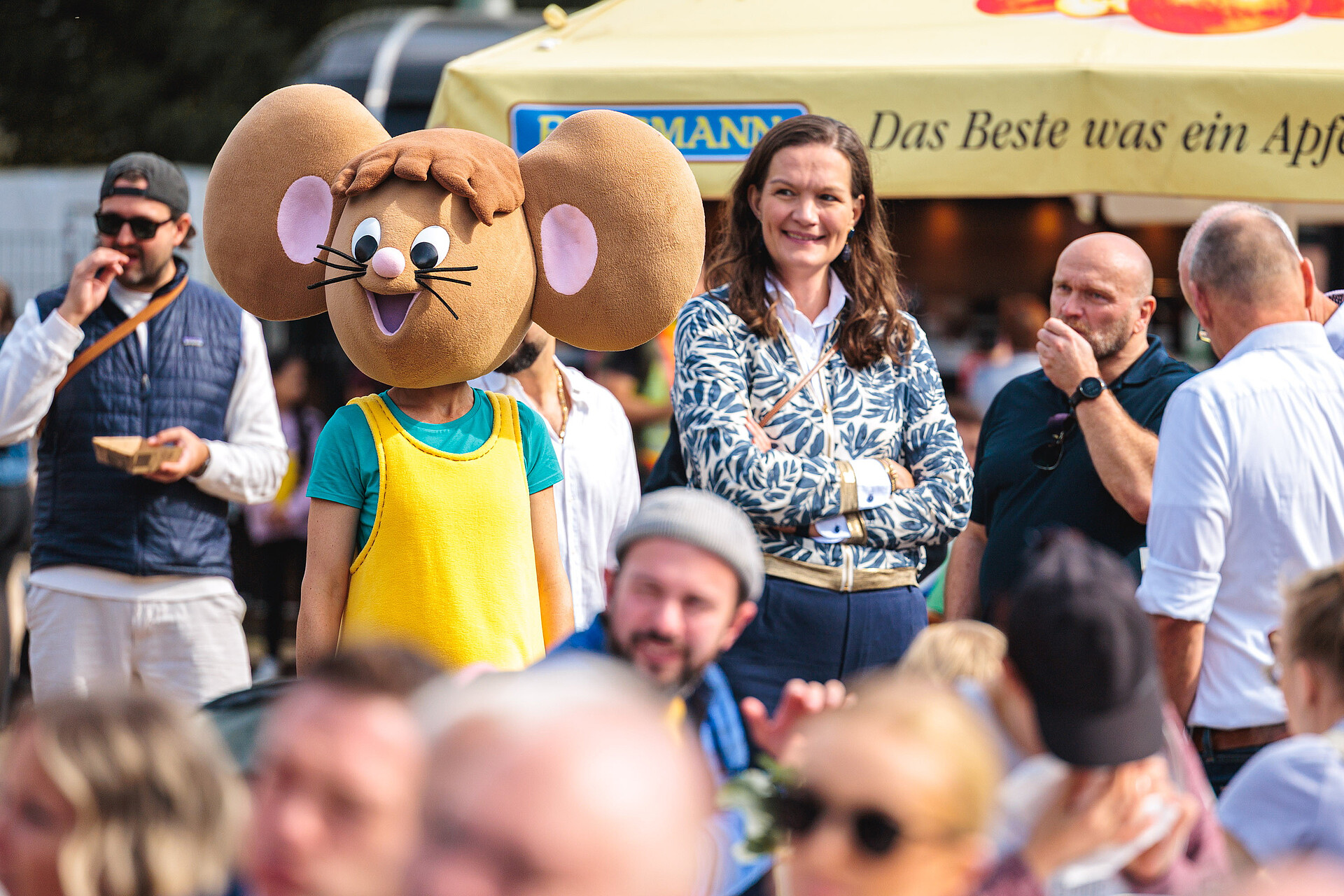 Die Maus Lisa steht inmitten von Gästen auf der 30 Jahre VGF-Feier