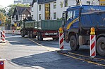 Blauer LKW und grüner Container auf Rädern auf einer Straße vor einem Mietshaus
