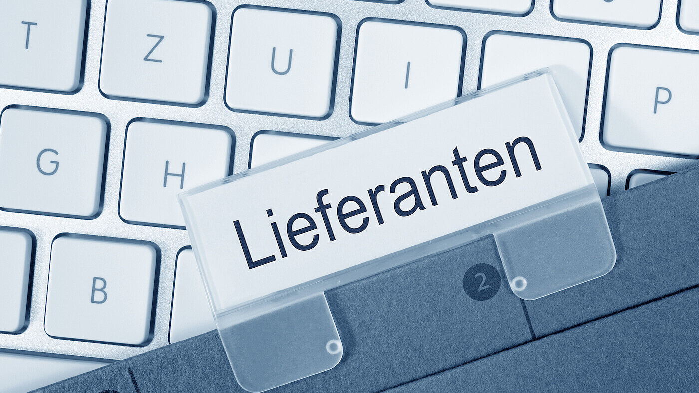 Das Bild zeigt eine Computer-Tastatur und ein Register mit dem Namen Lieferant.