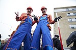Zwei Bauarbeiter auf Stelzen in Blaumännern