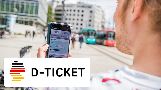 Mann mit Smartphone und der geöffneten VGF-Website. Im Bild ein Deutschlandumriss mit der Aufschrift D-Ticket (Deutschlandticket)