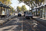 Straße mit Autos auf Schienen vor einer VGF-Haltestation
