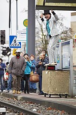 Artist im Nadelstreifenanzug und Zylinder auf dem Kopf an einer VGF-Haltestelle