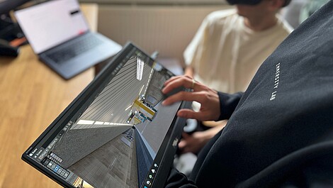 Immersity Lab Man sieht den Bildschirm eines Laptops. Auf dem Bildschirm ist die Station Parlamentsplatz als virtuelle Version zu sehen.