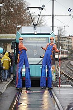 Zwei Bauarbeiter auf Stelzen vor einer VGF-U-Bahn