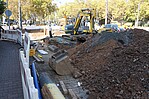 Ganz viel Erde und ein Bagger an einer Baustelle mit Absperrpfosten