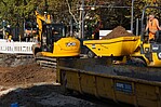 Bagger und Container an einer Straßenbaustelle bei sonnigem Wetter