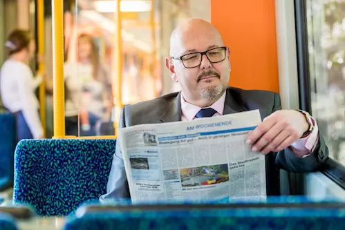 [Translate to English:] Businessman liest Zeitung in der Bahn