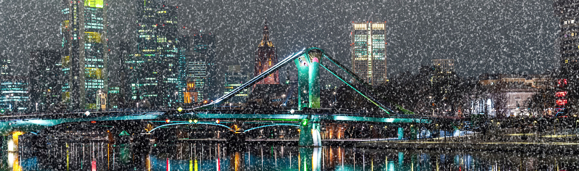 Skyline Frankfurt am Main bei Nacht mit einer Brücke im Vordergrund und Schnee im Bild