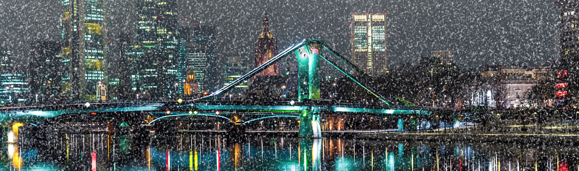 Skyline Frankfurt am Main bei Nacht mit einer Brücke im Vordergrund und Schnee im Bild