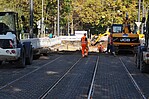 Straße mit einem Bauarbeiter und Baugeräten bei der Arbeit