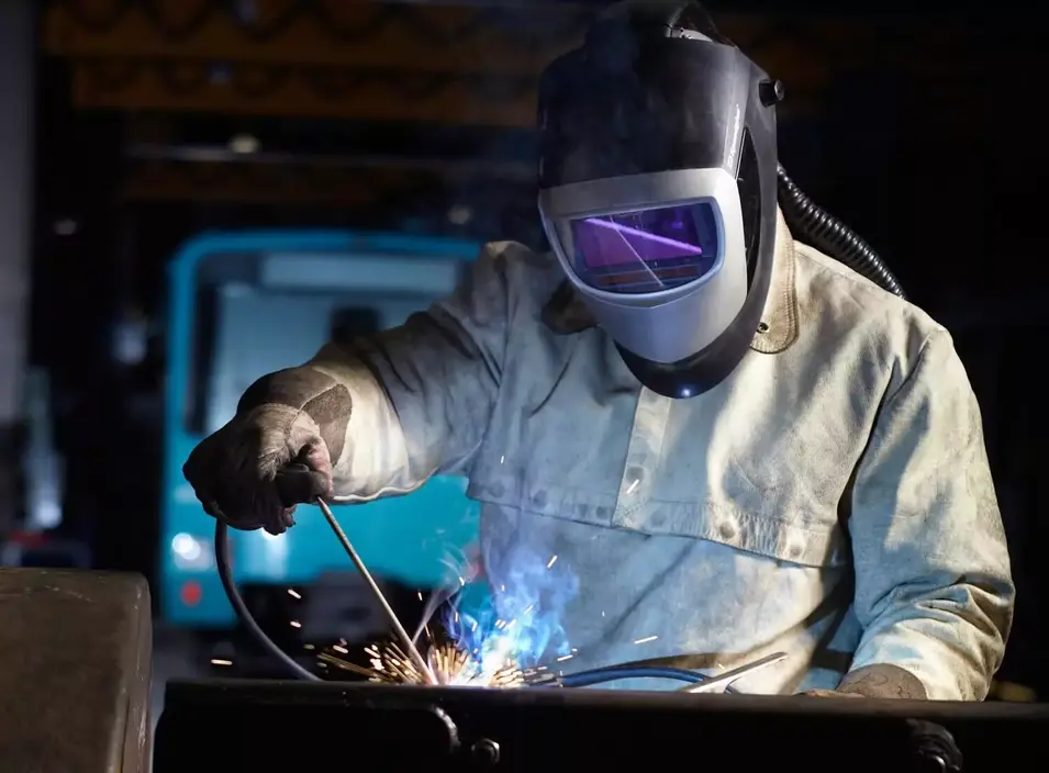 Das Bild zeigt einen Schweißer in Sicherheitsbekleidung.