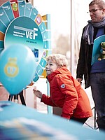 Blondes Kind vor einem VGF-Glücksrad