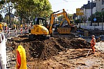 Baustelle mit Bauarbeitern und gelben Bagger beim Arbeiten an einer Straße
