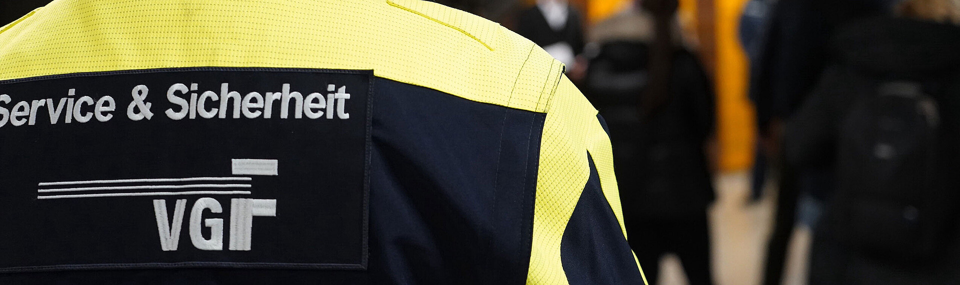 Sicherheitsbeamter der VGF mit dem Rücken zur Kamera an einer Haltestelle