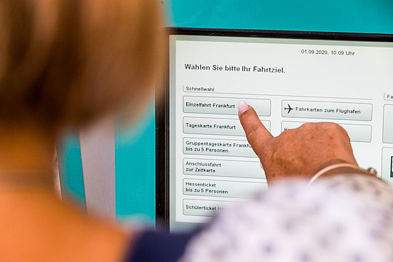 Ältere Dame beim Kauf einer RMV-Fahrkarte für Frankfurt am Display eines VGF-Automaten
