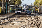 Baustelle mit Straßenaufbruch an einer Haltestelle und zwei Autos