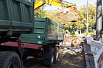 Grüner kleiner LKW auf einer Baustelle mit grünen Bäumen im Hintergrund