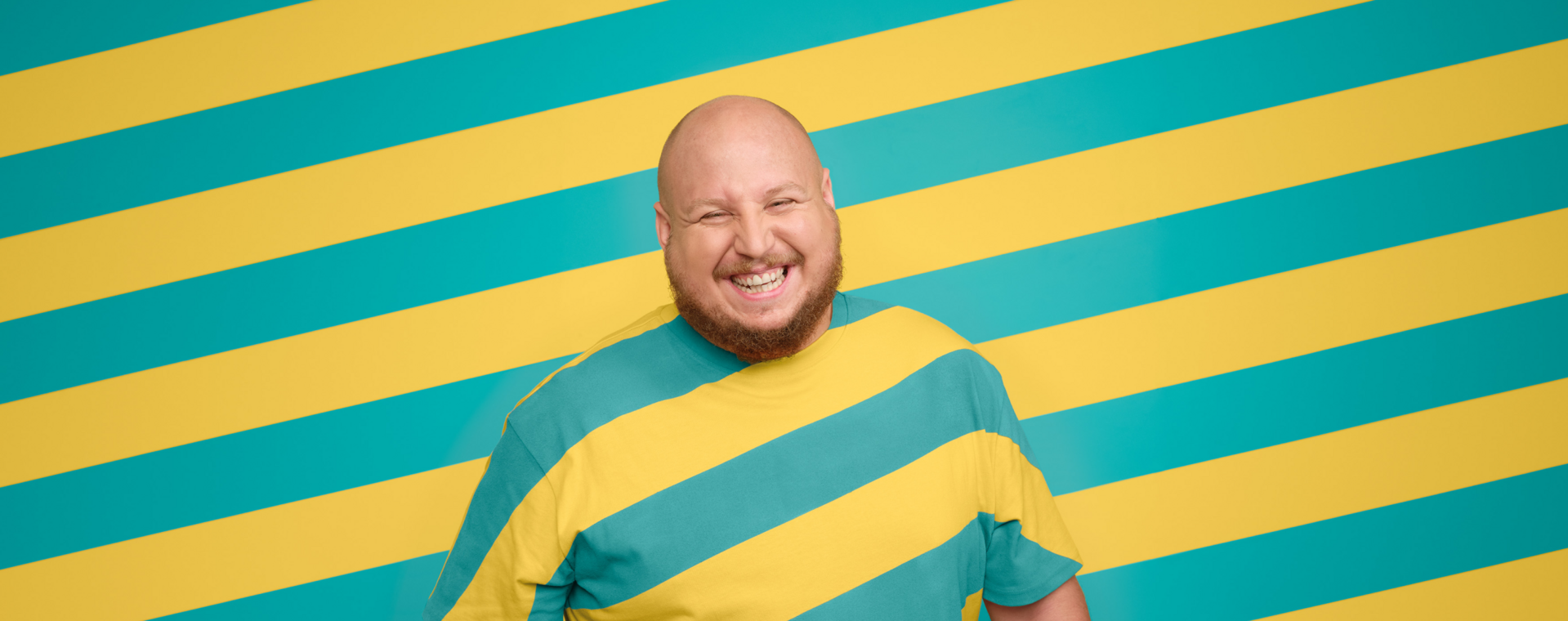 Das Bild zeigt einen Mitarbeitenden der VGF vor einem gestreiften Hintergrund