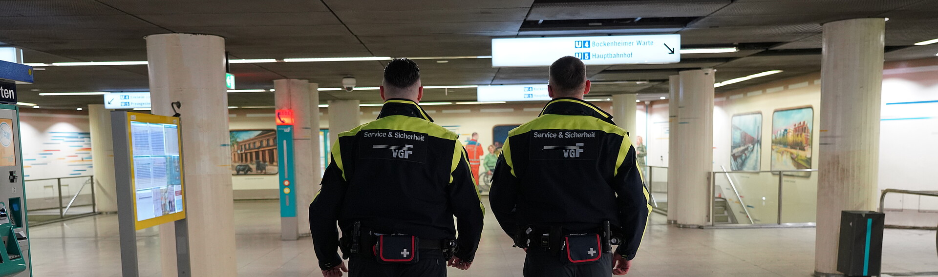 Zwei Sicherheitsbeamte der VGF von hinten bei einer Haltestelle