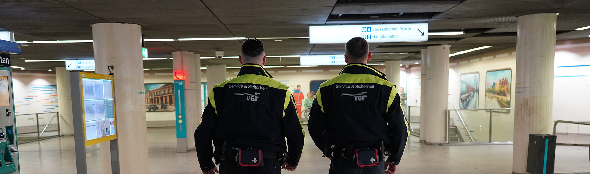 Zwei Sicherheitsbeamte der VGF von hinten bei einer Haltestelle